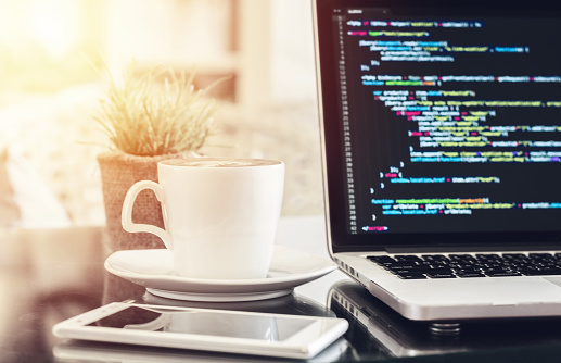 A laptop with source codes display in a coffee shop. Technology, Freelance Work, Web Design Business, and Web Development Concept.