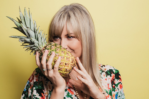 Woman in studio with yellow background with summer fashion and pineapple fruit
Photo taken with strobe light. Bright vivid portrait of mid adult woman in her 30s.