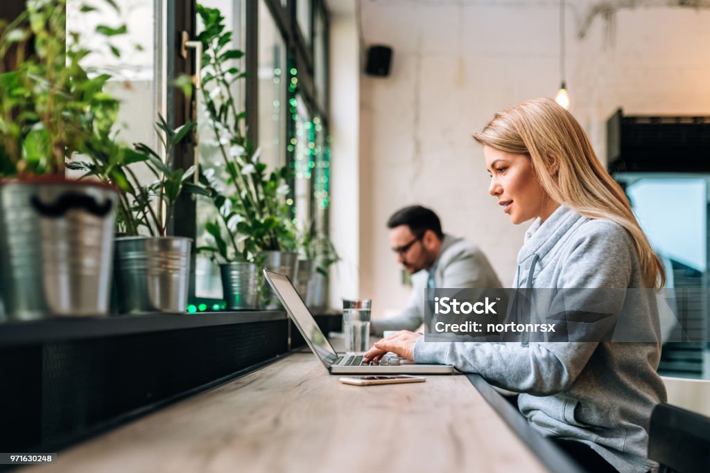 Concentrated blonde female copywriter working on creative task at the cafe. Cafe Stock Photo