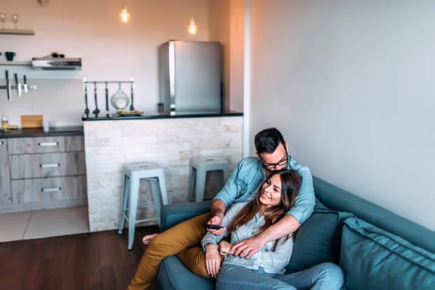 coppia carina coccolarsi mentre guarda la tv. - house kissing women residential structure foto e immagini stock