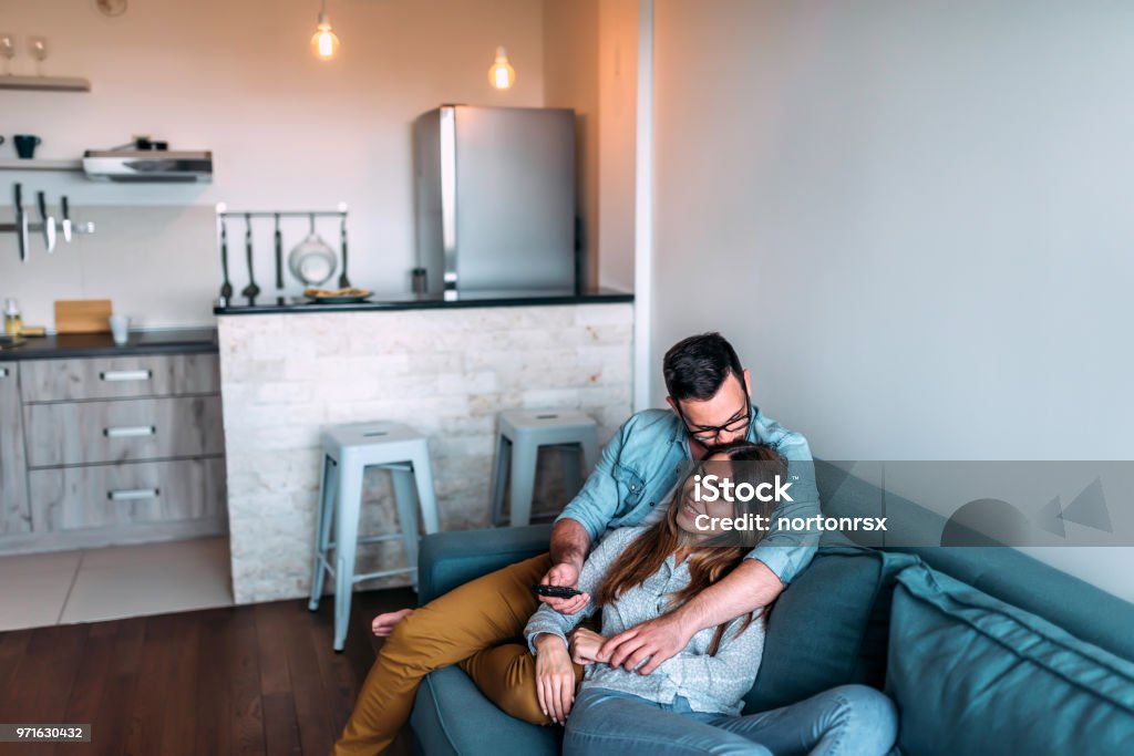 Cute couple cuddling while watching tv. Couple - Relationship Stock Photo