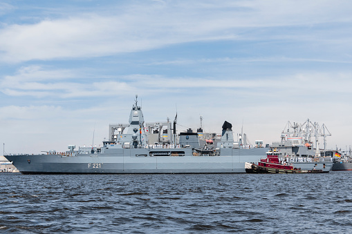 Russia, St. Petersburg, 28 July 2022: A several modern warships anchored at the Neva River embankment during the Navy Day celebrations in sunny weather, sailors on deck in festive uniforms