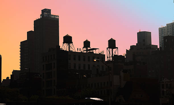 Rooftops with water tanks in silhouette against colorful sky stock photo