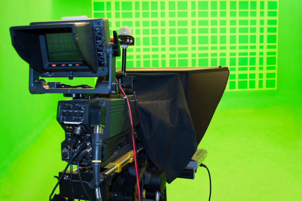 istock Broadcast television studio camera in green screen studio room with LED lights on the ceiling. 971694454
