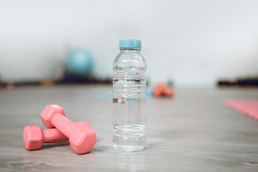 A Bottle Of Fresh Water And Dumbbells In Gym