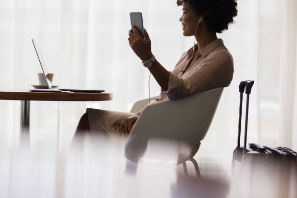 woman at airport lounge making video call - people traveling business travel waiting airport imagens e fotografias de stock