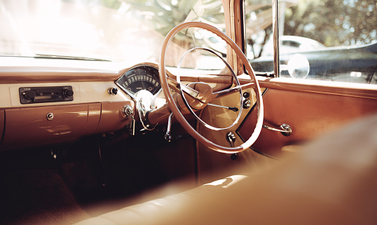 Interior of a classic vintage car. Retro style steering wheel with brown and beige dashboard.