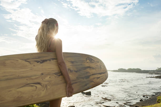 istock Young lady with surfboard watching the waves 971788654