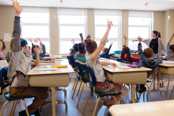 istock Multi-ethnic students sit into the class with arms raised 971801652
