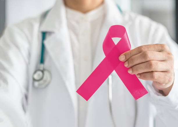 fita rosa para conscientização do câncer de mama na mão do médico, cor de arco simbólico para criar campanha de conscientização sobre a vida de pacientes mulheres (fêmea) com doença de tumor de mama - illness x ray image chest x ray - fotografias e filmes do acervo