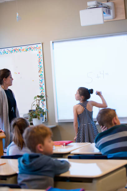 istock Shcoolgirl writing lesson in interactive whiteboard in classroom 971802272