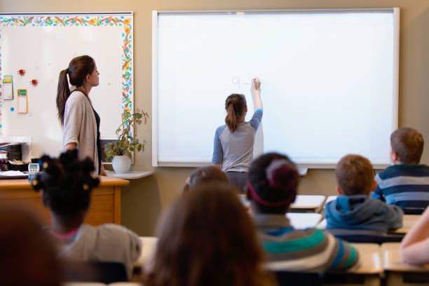 istock Shcoolgirl writing lesson in interactive whiteboard in classroom 971804314