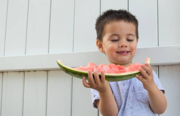 A young boy eating watermelon stock photo