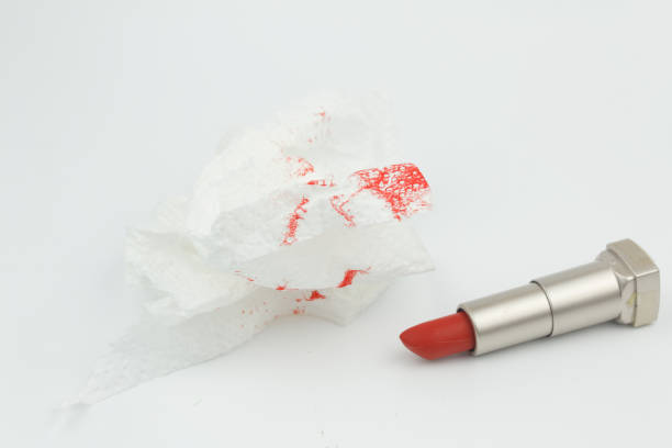 Red lipstick with tissue with red lipstick stain on isolated white background