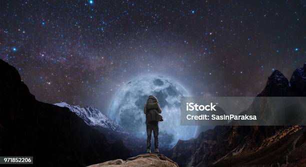 Un Hombre Con La Situación De La Mochila En El Pico De La Montaña En La Noche Y Montaña De Silueta Con Luna Llena Brillante Y Un Cielo Lleno De Estrellas Foto de stock y más banco de imágenes de Soñar despierto