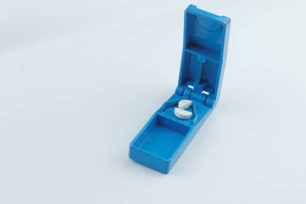 Blue tablet cutter with cut tablet inside it on isolated white background