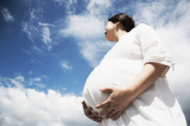 istock Pregnant woman relaxed under blue sky 971891884