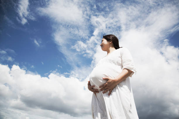 istock Pregnant woman relaxed under blue sky 971891914