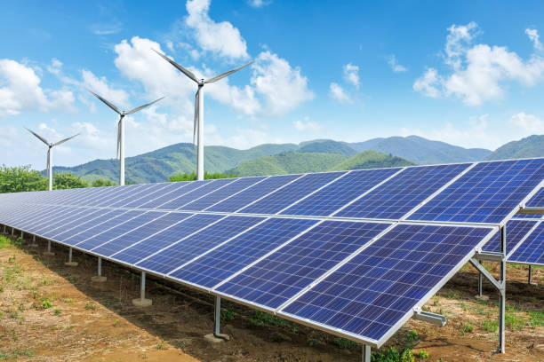 istock Solar panels and wind turbines with mountains landscape 971903478