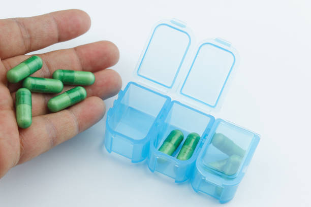istock Blue pill / medication / tablet box with green capsule on isolated white background. 971919682