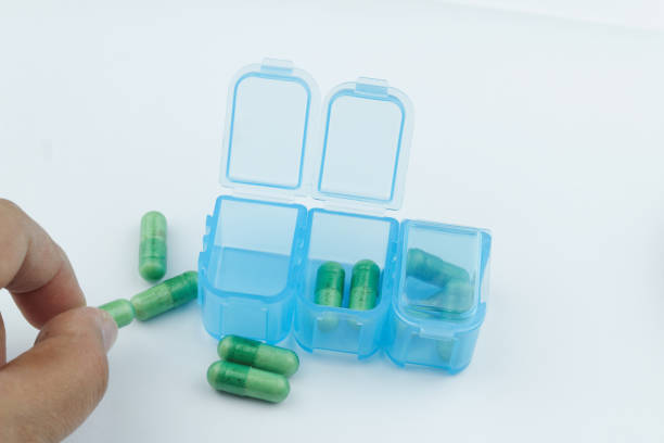 istock Blue pill / medication / tablet box with green capsule on isolated white background. 971921990