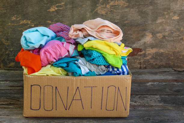 istock Donation box with clothes on the old wooden background. 971931814