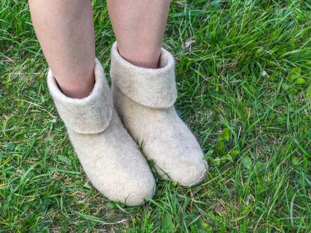istock Cold summer. Women's feet in felt boots on the green grass background 971931950