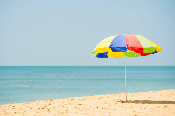 A colorful umbrella is open on a tropical beach during a sunny day.
