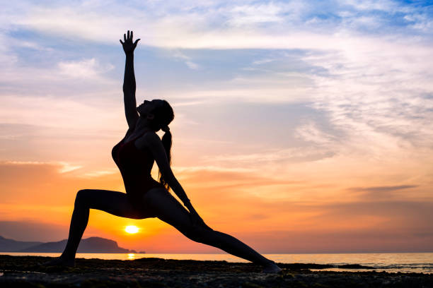istock Silhouette young woman practicing yoga on the beach at sunset 971934890