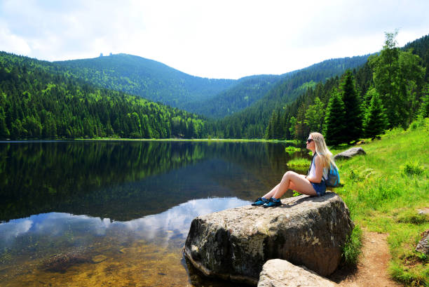 Tourist sitting on stone by moraine lake Kleiner Arbersee.Germany. Tourist sitting on stone by moraine lake Kleiner Arbersee in National park Bavarian forest. Germany. bavarian forest stock pictures, royalty-free photos & images