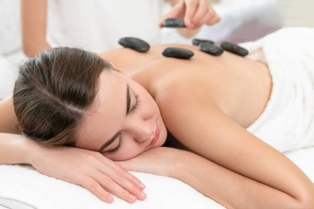 istock Hot stone massage treatment by therapist in spa. 971952668