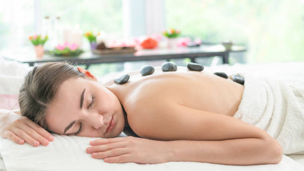 istock Hot stone massage treatment by therapist in spa. 971952720