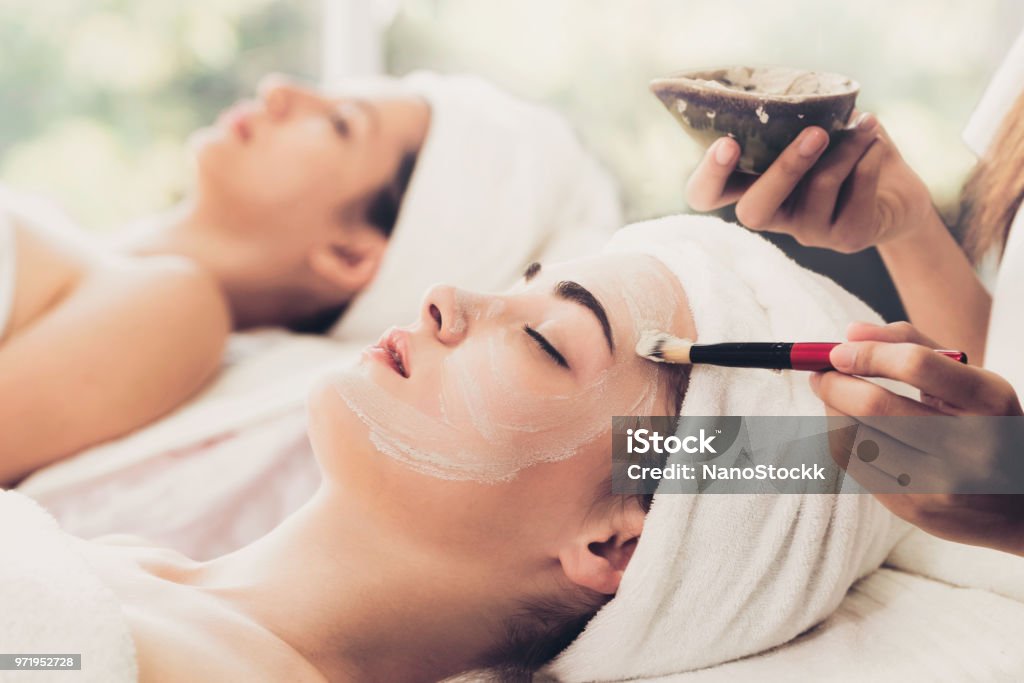 Beautiful woman having a facial treatment at spa. Beautiful woman having a facial cosmetic scrub treatment from professional dermatologist at wellness spa. Anti-aging, facial skin care and luxury lifestyle concept. Mask - Disguise Stock Photo