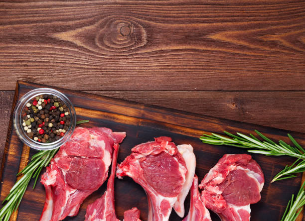 istock Raw lamb cutlets on bone on dark brown wooden background, lamb ribs, top view, copy space. 971955166