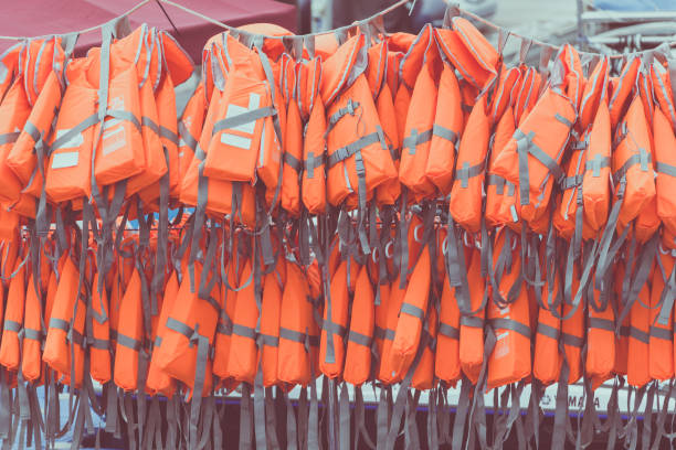 istock Orange new life jackets for waters sport are hanging on port. 971955708