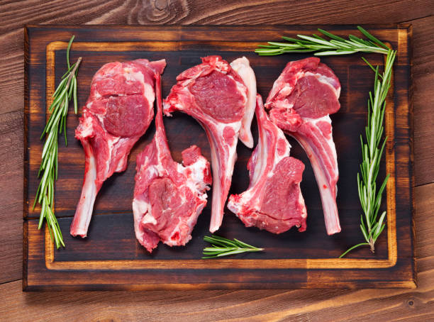 istock Raw lamb cutlets on bone on dark brown wooden background, lamb ribs, top view. 971961302