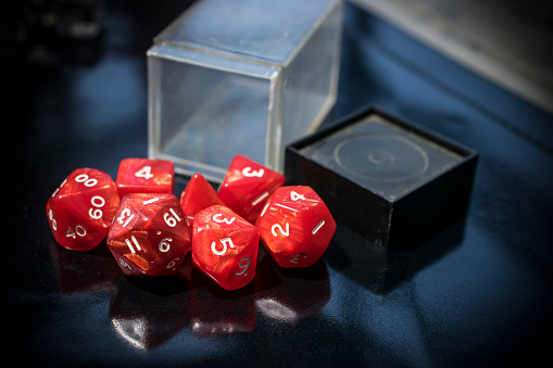 A container with spilled red RPG dice on a black table