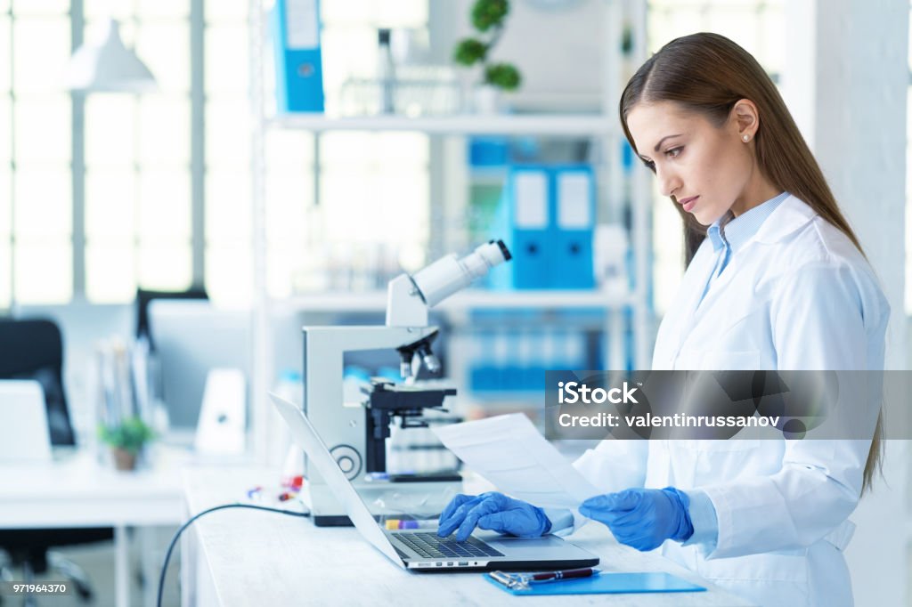 Scienziata donna che usa laptop in laboratorio - Foto stock royalty-free di Laboratorio