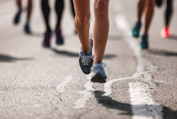 nicht erkennbare marathon-läufer in bewegung auf der straße. - langstreckenlauf stock-fotos und bilder