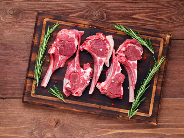 istock Raw lamb cutlets on bone on dark brown wooden background, lamb ribs, top view. 971969748