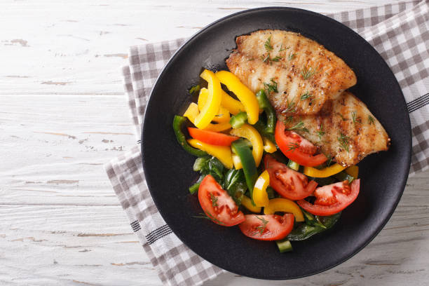 istock Grilled fish steaks and fresh vegetable salad close-up. horizontal top view 971986418