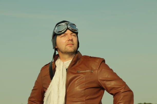 Vintage pilot with leather cap, scarf and aviator glasses  - Portrait of a man in historical pilot clothing stock photo