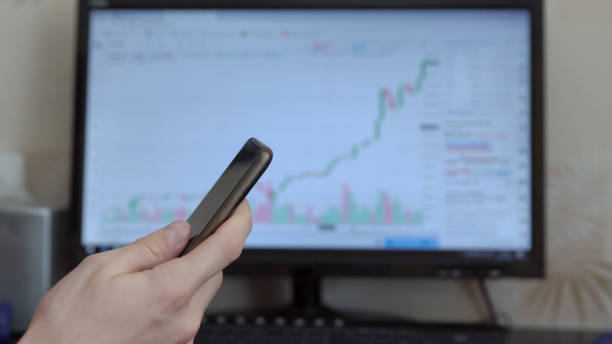 istock Man with phone in hands on computer monitor background 972000610
