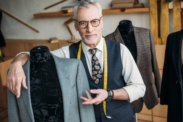 istock handsome tailor showing jacket on mannequin at sewing workshop 972009862