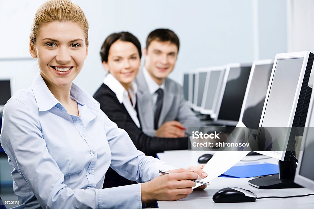 Students learning by using the computer  Three mature students sitting in a row in the computer classroom with smiles Achievement Stock Photo