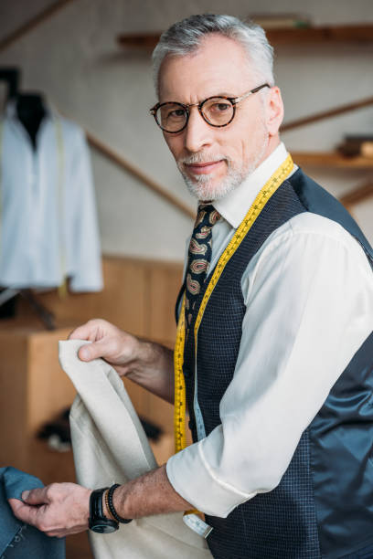 istock grey hair tailor choosing cloth at sewing workshop 972016634