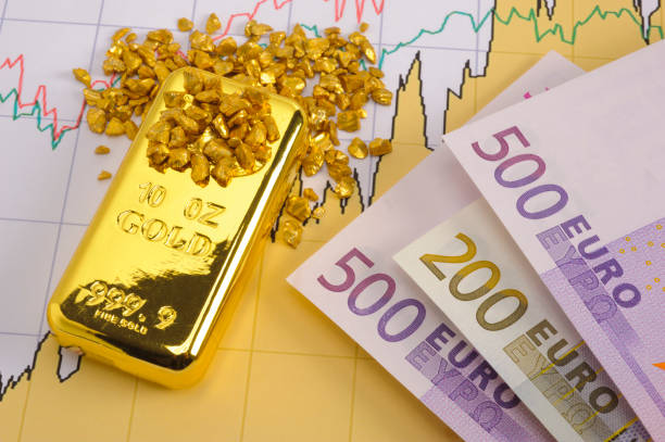 gold bar and European currency laying on chart of stock market stock photo