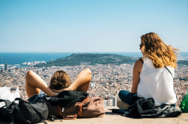 View of Barcelona, the Mediterranean sea, Sagrada Familia, Catalonia, Spain. Barcelona, Catalonia, Spain - May 30, 2015: Couple of tourists sit on the viewpoint look from the above of Barcelona city and enjoy of cityscape from Bunker El Carmel or Turo de la Rovira. Catalonia, Spain. parallel port stock pictures, royalty-free photos & images