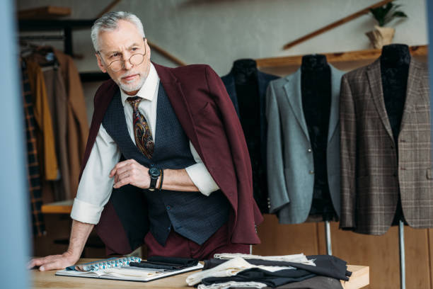 istock handsome mature tailor with jacket on shoulders at workplace in sewing workshop 972032036