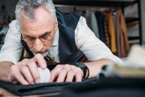 istock close-up shot of handsome mature tailor marking cloth pattern with chalk at sewing workshop 972032506